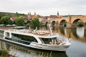 Bateau de croisière fluviale Rivages du Monde naviguant sur un fleuve européen avec terrasse panoramique et passagers en train de se détendre